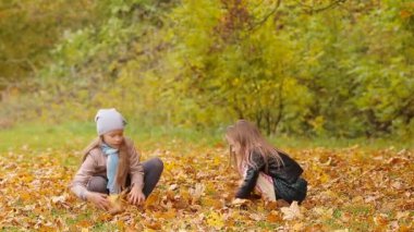 Küçük sevimli kızlar eğleniyor yaprakları ile sonbahar park açık havada sıcak gün