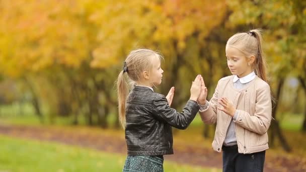 Pequenas garotas adoráveis se divertindo no dia quente no parque de outono ao ar livre — Vídeo de Stock
