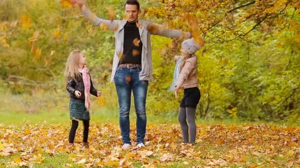 Familia feliz divirtiéndose y tirando hojas alrededor en un día de otoño al aire libre — Vídeo de stock