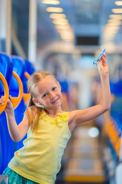 Adorável menina viajando no trem e se divertindo com o modelo de avião nas mãos — Fotografia de Stock