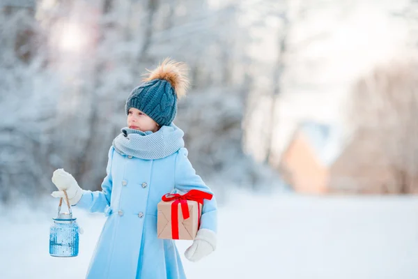 Dziewczynka gospodarstwa Christmas Latarnia i prezent na nowy rok na zewnątrz na piękny zimowy dzień śniegu — Zdjęcie stockowe