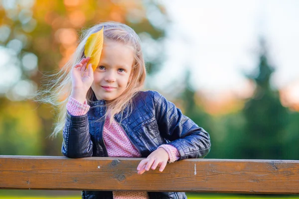 Portrait d'adorable petite fille avec feuille jaune à l'extérieur à la belle journée d'automne — Photo