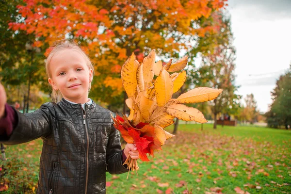 Adorable little girl taking selfie portrait with yellow and orange leaves bouquet outdoors at beautiful autumn day — Stock Photo, Image