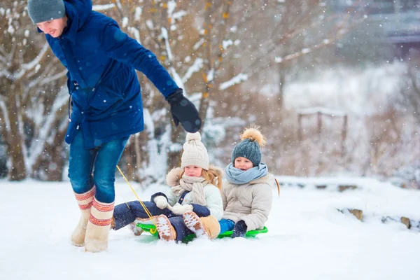 Pikkutytöt nauttivat kelkkailusta talvipäivänä. Perheloma jouluaattona ulkona — kuvapankkivalokuva