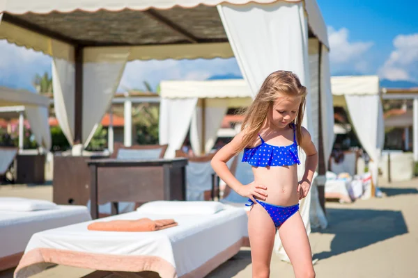 Adorable happy smiling little girl on beach vacation near sunbeds — Stock Photo, Image