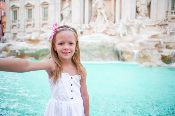 Adorable niña tomando selfie junto a la Fuente de Trevi en Roma. Feliz niña disfrutar de sus vacaciones europeas en Italia —  Fotos de Stock