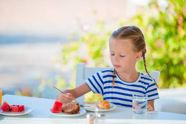 Niña adorable desayunando en la cafetería con vista al mar temprano en la mañana — Foto de Stock