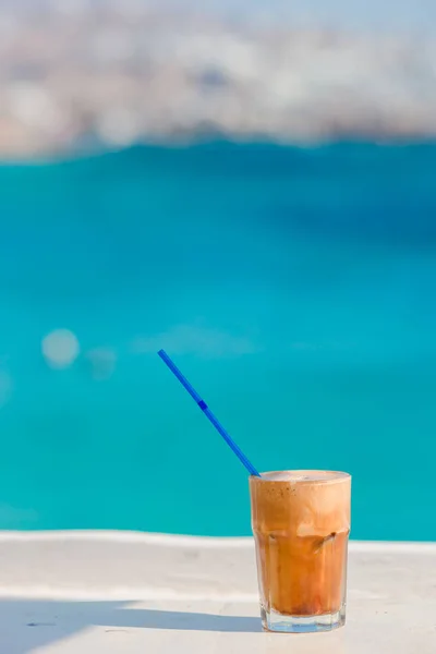 Frappe, ice coffee on the beach. Summer iced coffee frappuccino, frappe or latte in a tall glass background the sea in beach bar — Stock Photo, Image