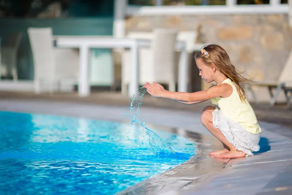 Schattig klein meisje met plezier met een plons in de buurt van zwembad — Stockfoto