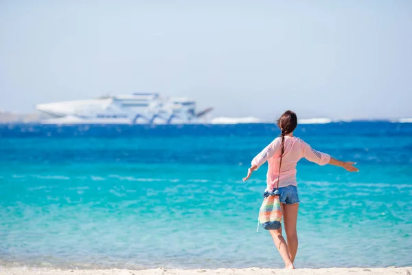 Ung flicka på stranden bakgrunden stora kryssningsfartyget. Kvinna njuta av sin wekeend på en av de vackra stränderna i Grekland, Europa. — Stockfoto