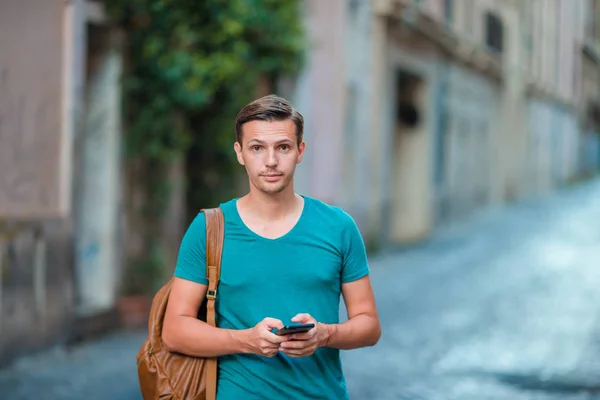 Kavkazská chlapec drží mobil venku na ulici. Člověk používající mobilní smartphone. — Stock fotografie