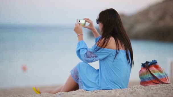 Jonge vrouw Neem een foto op telefoon op het strand in de avond — Stockvideo