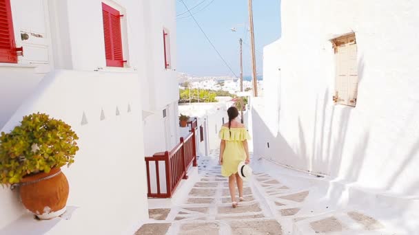 Mooie vrouw buitenshuis in oude straten een Mykonos. Meisje op straat van typische Griekse traditionele dorp met witte wanden en kleurrijke deuren op het eiland Mykonos, in Griekenland, Europa — Stockvideo