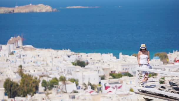 Gyönyörű fiatal nő olvasókönyv a luxus szálloda, gyönyörű kilátással a Mykonos, Görögország — Stock videók