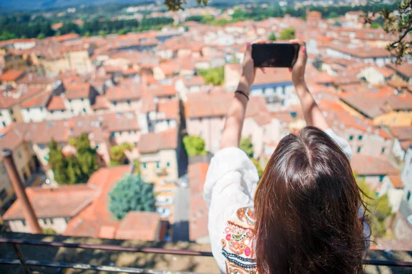 Young caucasian woman making photo of european old city by mobile phone from the observation place — Stock Photo, Image