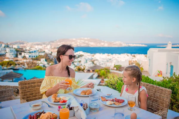 Familia desayunando en la cafetería al aire libre con una vista increíble. Adorable chica y madre comiendo croissant en la terraza del hotel de lujo —  Fotos de Stock