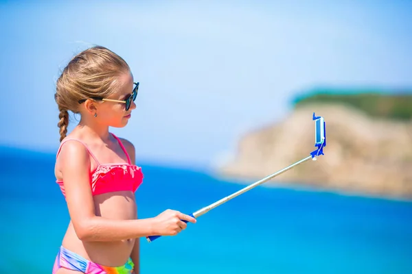 Malá holčička s selfie ve svém smartphonu na pláži. Kid se těší její letní dovolenou a fotí pro paměť — Stock fotografie