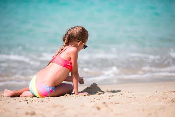 Urocza dziewczynka rysunek na piasku na plaży podczas letnich wakacji — Zdjęcie stockowe