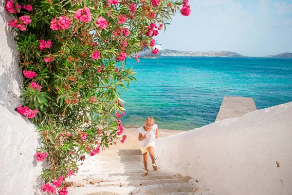 Adorable girl having fun outdoors. Kid at street of typical greek traditional village with white walls and colorful doors on Mykonos Island, in Greece — Stock Photo, Image