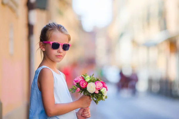 Entzückendes kleines Mädchen mit Blumenstrauß zu Fuß in der europäischen Stadt — Stockfoto