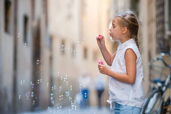 Adorabile bambina all'aperto che soffia bolle di sapone nella città europea. Ritratto di bambino caucasico godersi le vacanze estive in Italia — Foto Stock