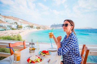 Genç kadın lezzetli taze salata, frappe ve liman ve deniz üzerinde güzel manzaralı açık restaurant, öğle yemeği için hizmet brusketa ile öğle yemeği