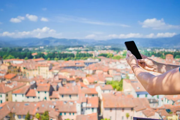 特写的男性手拿着手机背景古老的意大利小镇。使用手机的人. — 图库照片