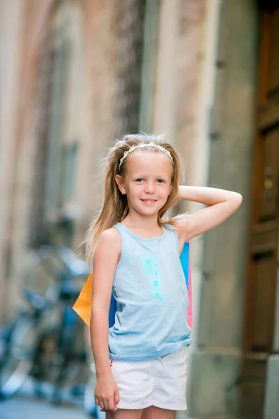 Portret urocza dziewczynka chodzenie z torby na zakupy na zewnątrz w europejskim mieście. Mody toddler dziecko w włoskiego miasta z jej zakupy — Zdjęcie stockowe