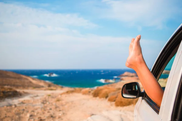 Close up van weinig meisje voeten tonen van de auto venster achtergrond zee — Stockfoto