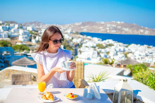 Linda senhora elegante tomando café da manhã no café ao ar livre com vista incrível sobre a cidade de Mykonos. Mulher snjoy seu chá quente no início da manhã — Fotografia de Stock