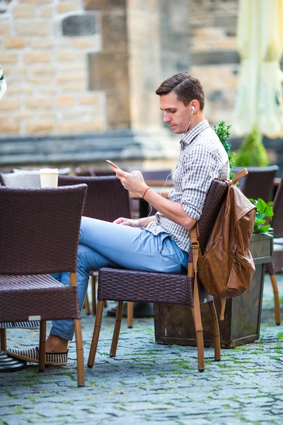Młody człowiek trzyma telefon na zewnątrz na ulicy. Facet za pomocą mobile smartphone. — Zdjęcie stockowe