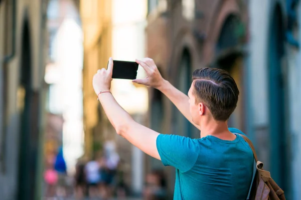 Hvit turist med smarttelefon i hånden som går langs de smale italienske gatene i Roma. Ung bygutt på ferie på utforskning av europeisk by – stockfoto