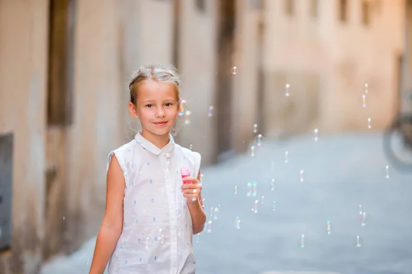 Niña soplando burbujas de jabón en la ciudad europea. Retrato de niño caucásico disfrutar de vacaciones de verano en Italia —  Fotos de Stock