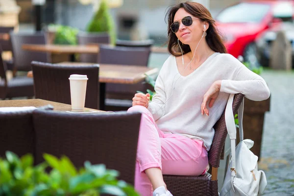 Young caucasian girl listening music in outdoor cafe — Stock Photo, Image