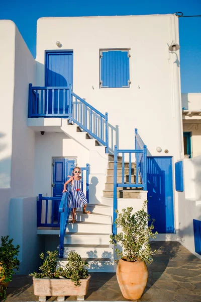 Typický dům s modrým balkony, schody a květiny. Malá holka na schodech v tradiční řecké domě. Krásnou architekturou v exteriéru s kykládském stylu. — Stock fotografie