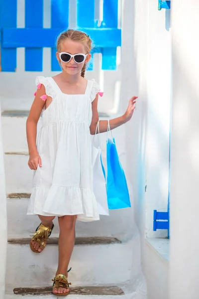 Adorable girl in white dress at street of typical greek traditional village with white walls and colorful doors in Greece — Stock Photo, Image