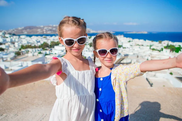 Two girls taking selfie photo outdoors with amazing view on greek village and sea — Stock Photo, Image