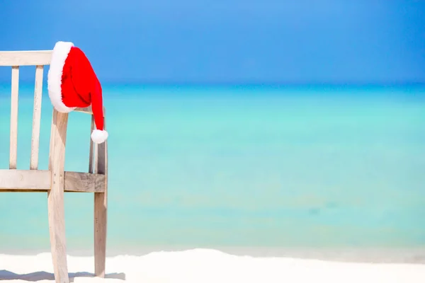 Санта-Клаус на шезлонге возле пляжа с бирюзовой морской водой и белым песком. Рождественские каникулы — стоковое фото