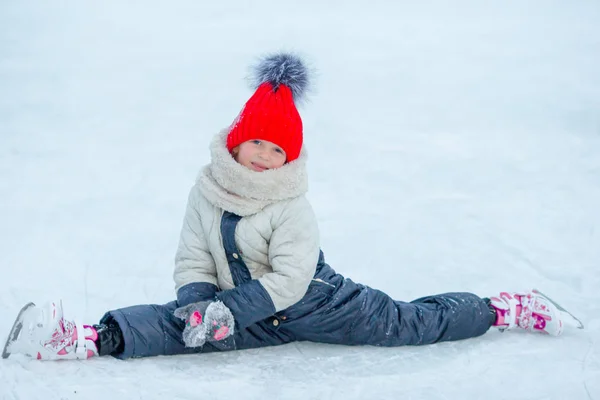Schattig meisje zitten op ijs met schaatsen na val — Stockfoto