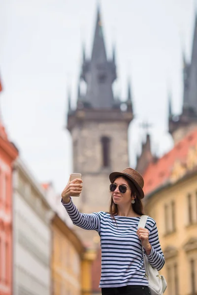 Menina feliz tomando selfie fundo famoso castelo na cidade europeia. Turista caucasiano caminhando pelas ruas desertas da Europa . — Fotografia de Stock