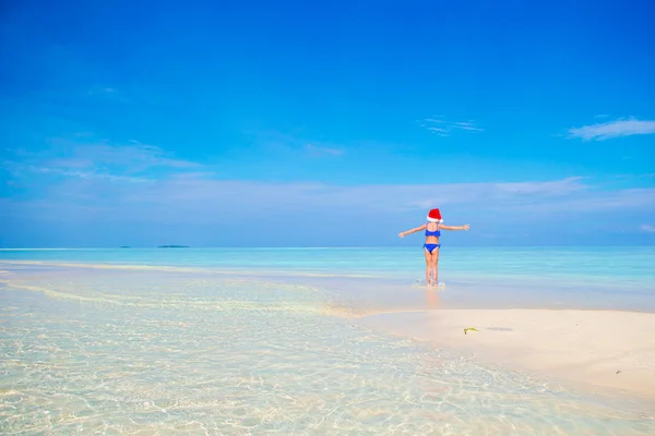 Klein meisje in KERSTMUTS op witte strand tijdens kerst vakantie — Stockfoto