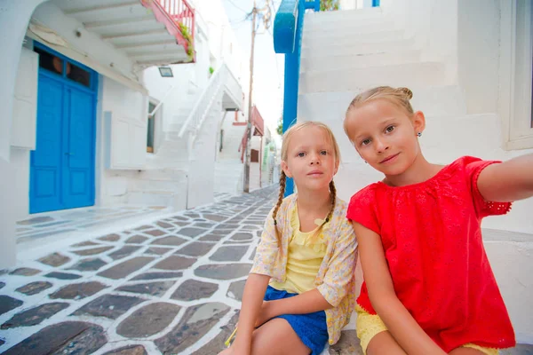 Two girls taking selfie photo outdoors in greek village on narrow street — Stock Photo, Image