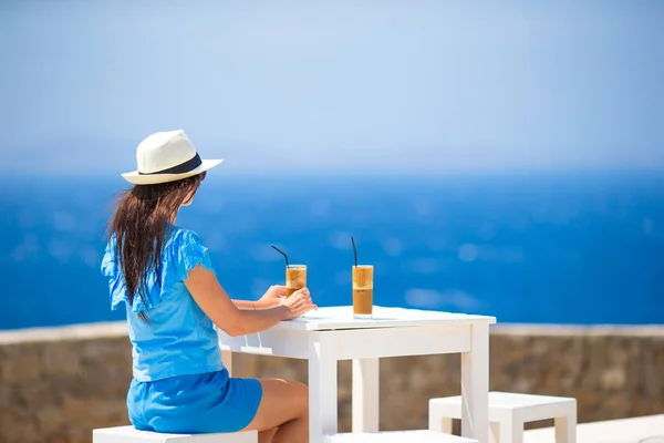 Jovem no café ao ar livre bebendo café frio desfrutando de vista mar . — Fotografia de Stock