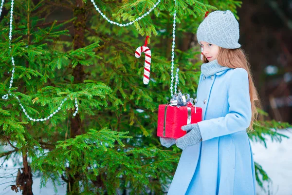 Adorable girl with Christmas box gift in winter outdoors on Xmas eve — Stock Photo, Image