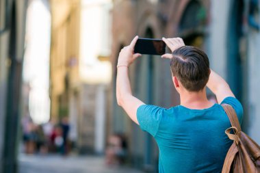 Turist adam alarak fotoğraf smartphone Avrupa'da dar İtalyan sokaklar boyunca yürüyüş elinde. Avrupa şehri keşfetmek tatil genç kentsel çocuk