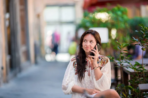 Portret piękna kobieta siedzi w kawiarnię na świeżym powietrzu picia kawy i rozmawiać przez smartfona. — Zdjęcie stockowe