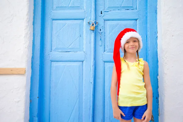 Menina em santa chapéu ao ar livre na rua velha em férias de Natal em Mykonos . — Fotografia de Stock