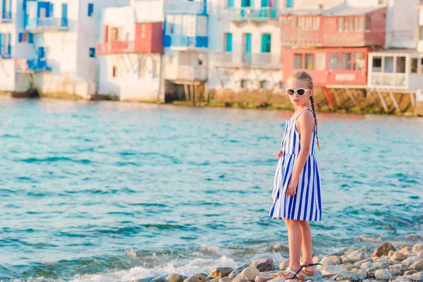 Rozkošná holčička v Malé Benátky nejoblíbenější turistická oblast na ostrově Mykonos, Řecko. Krásné dítě úsměv a podívejte se do kamery na Malé Benátky pozadí. — Stock fotografie