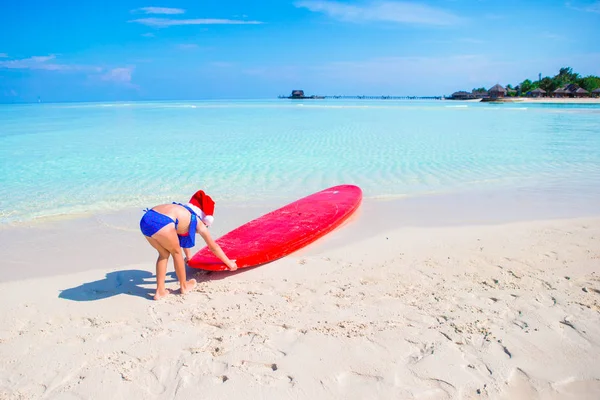 小女孩在圣诞老人的帽子在热带度假海滩度假期间 — 图库照片