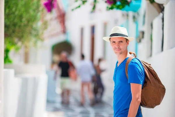 Turista caucásico caminando por las estrechas calles de Mykonos. Joven chico urbano de vacaciones explorando la calle empedrada de la ciudad europea — Foto de Stock